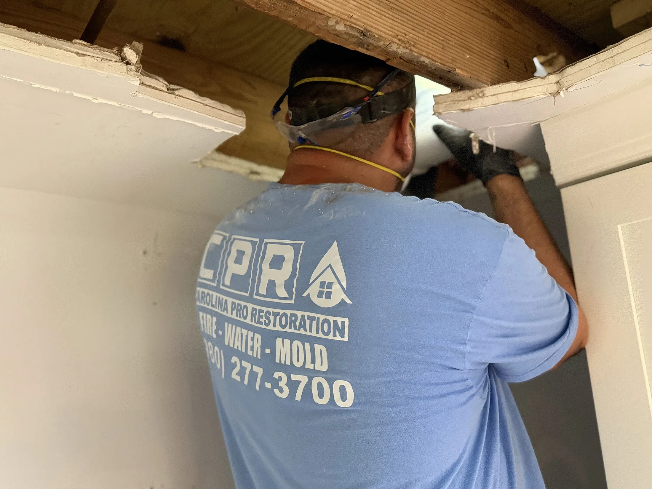 Technician opening a wall to repair burst-pipe water damage